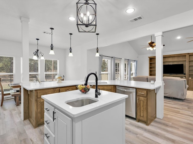 kitchen with stainless steel dishwasher, ceiling fan with notable chandelier, an island with sink, and light hardwood / wood-style flooring