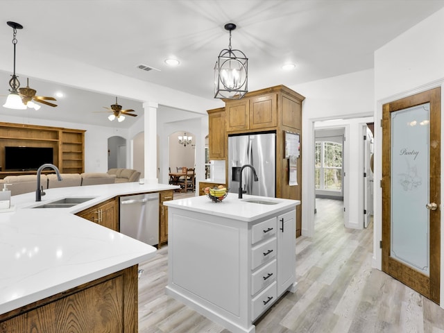 kitchen featuring light hardwood / wood-style flooring, ceiling fan with notable chandelier, appliances with stainless steel finishes, decorative light fixtures, and sink