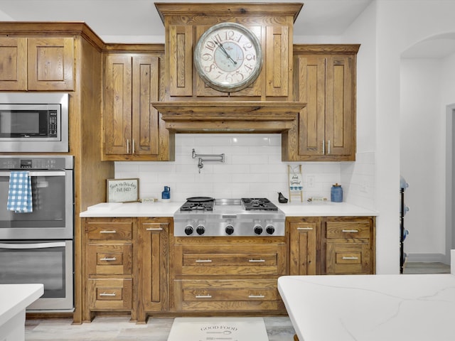 kitchen featuring stainless steel appliances, light hardwood / wood-style floors, and tasteful backsplash