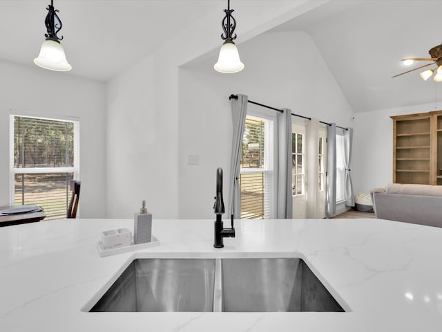 kitchen featuring sink, decorative light fixtures, a healthy amount of sunlight, and light stone counters