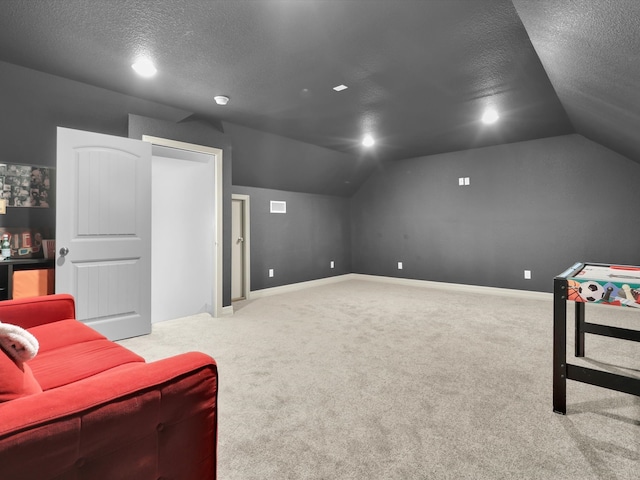 home theater featuring light carpet, vaulted ceiling, and a textured ceiling