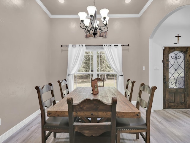 dining room featuring crown molding, light wood-type flooring, and an inviting chandelier