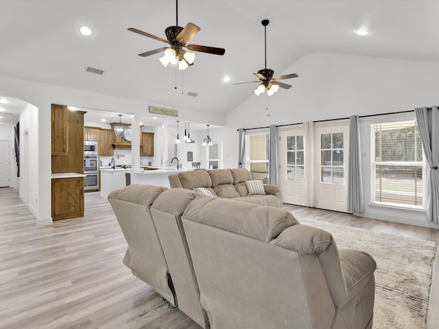 living room featuring light hardwood / wood-style floors, sink, ceiling fan, and high vaulted ceiling