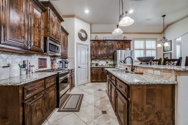 kitchen with hanging light fixtures, decorative backsplash, light stone counters, and stainless steel appliances