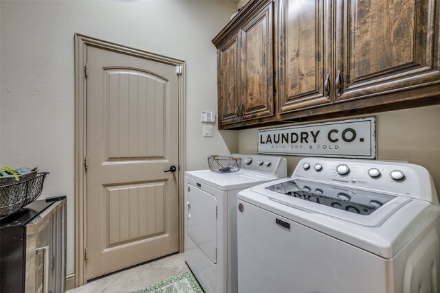 laundry area featuring separate washer and dryer, cabinets, and light tile patterned floors