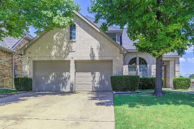 view of front of house with brick siding, roof with shingles, concrete driveway, an attached garage, and a front yard