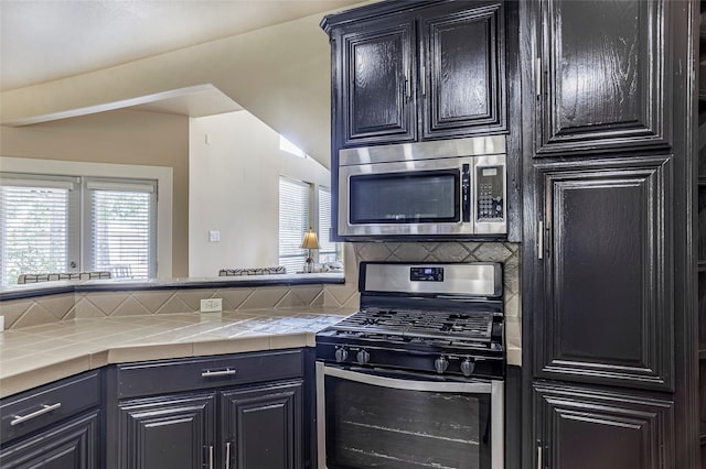 kitchen featuring decorative backsplash, appliances with stainless steel finishes, and tile counters