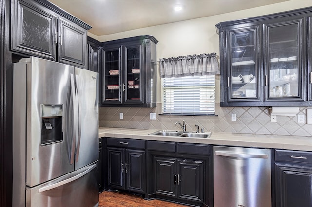 kitchen featuring appliances with stainless steel finishes, sink, decorative backsplash, light stone countertops, and dark hardwood / wood-style flooring