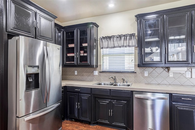 kitchen featuring glass insert cabinets, appliances with stainless steel finishes, light countertops, and a sink