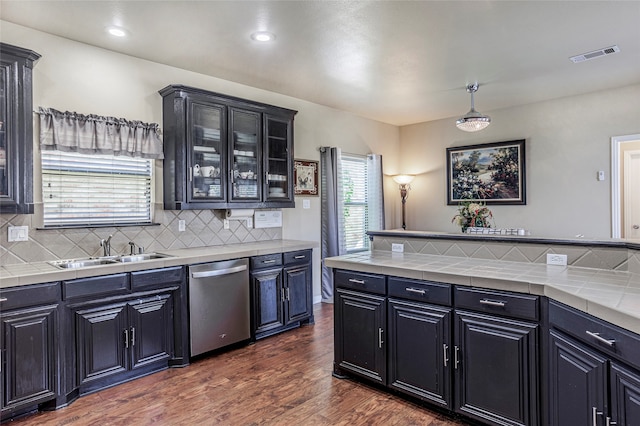 kitchen featuring decorative backsplash, dark wood-type flooring, tile countertops, and stainless steel dishwasher