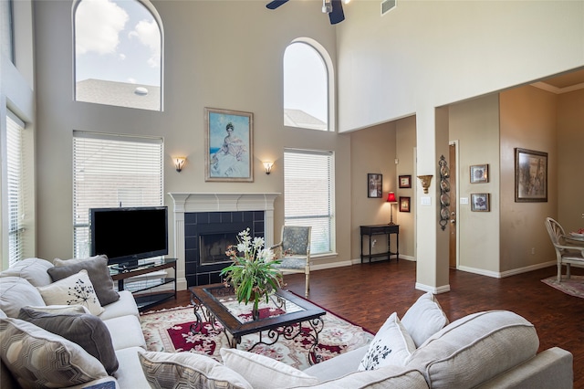 living room featuring hardwood / wood-style flooring, a healthy amount of sunlight, a tiled fireplace, and ceiling fan