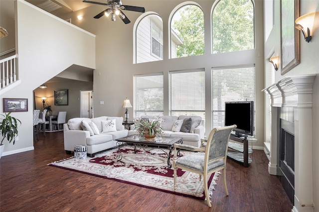 living room with dark wood-type flooring, a high ceiling, and ceiling fan