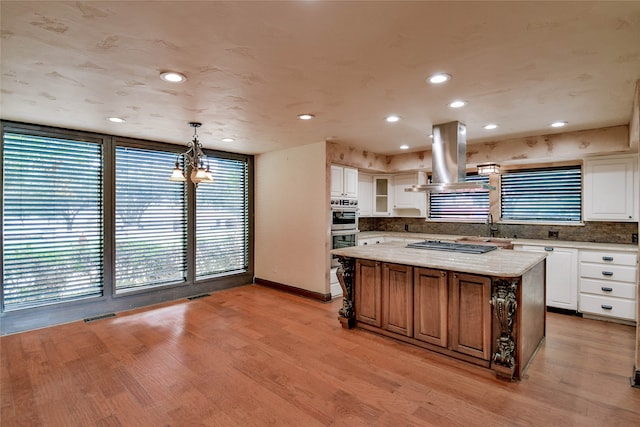 kitchen with a chandelier, light hardwood / wood-style floors, white cabinetry, a kitchen island, and island range hood