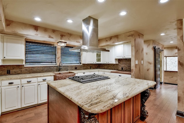 kitchen featuring island range hood, white cabinetry, a kitchen island, and sink