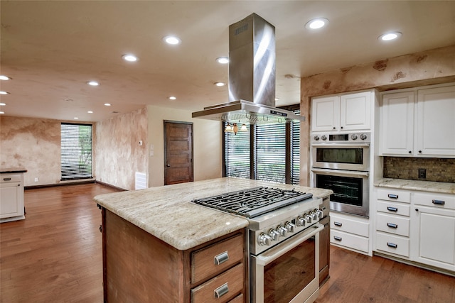 kitchen featuring white cabinets, appliances with stainless steel finishes, light stone countertops, dark hardwood / wood-style flooring, and island exhaust hood