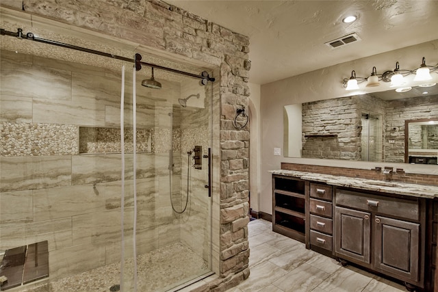 bathroom with a textured ceiling, vanity, and an enclosed shower