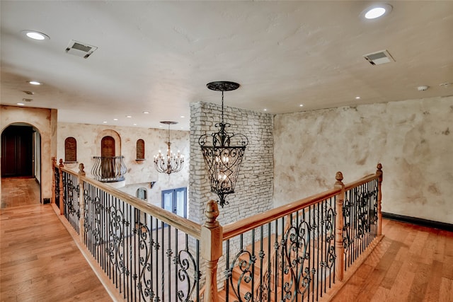 hall with wood-type flooring and a notable chandelier