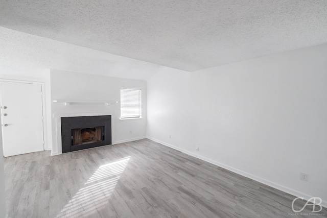 unfurnished living room featuring light wood-type flooring and a textured ceiling