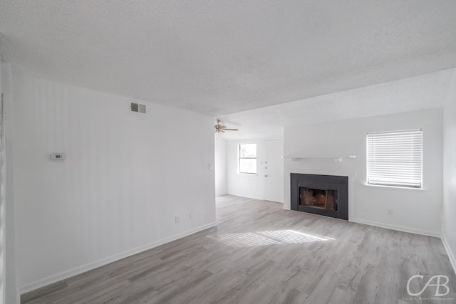 unfurnished living room with light wood-type flooring, ceiling fan, and a textured ceiling