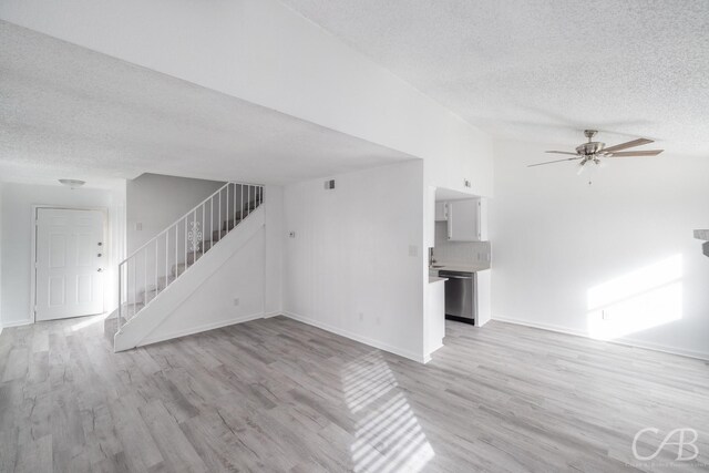 unfurnished living room with ceiling fan, a textured ceiling, and light hardwood / wood-style floors