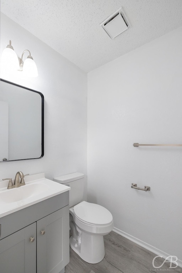 bathroom with hardwood / wood-style floors, toilet, vanity, and a textured ceiling