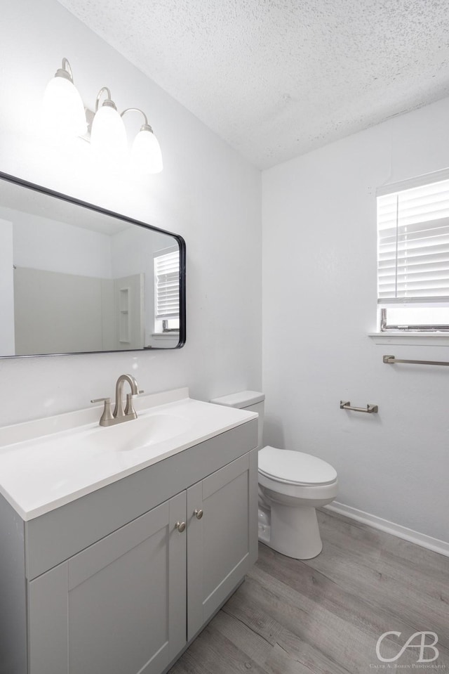 bathroom featuring a textured ceiling, toilet, hardwood / wood-style flooring, and vanity