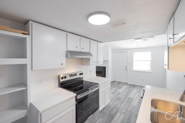 kitchen with a textured ceiling, white cabinetry, and electric range