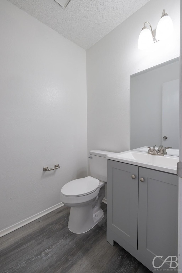 bathroom with a textured ceiling, toilet, hardwood / wood-style flooring, and vanity