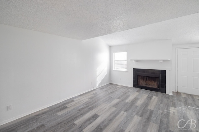 unfurnished living room featuring wood-type flooring, a textured ceiling, and a fireplace