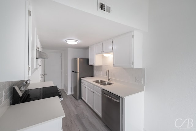 kitchen with appliances with stainless steel finishes, light hardwood / wood-style flooring, white cabinetry, and sink