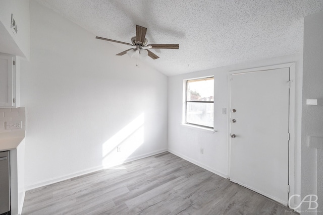 foyer entrance featuring ceiling fan, a textured ceiling, vaulted ceiling, and light wood-type flooring