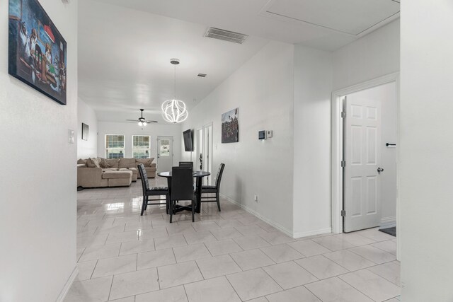 tiled dining room with ceiling fan with notable chandelier