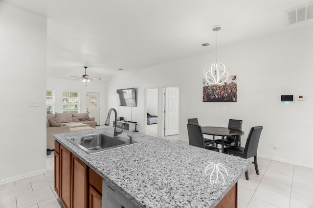 kitchen featuring hanging light fixtures, ceiling fan with notable chandelier, sink, light tile patterned floors, and a kitchen island with sink