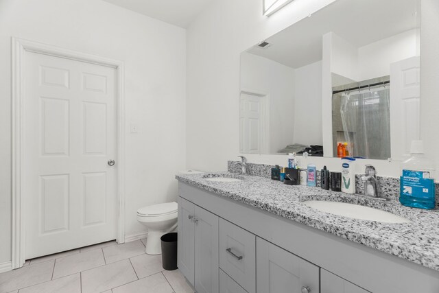 bathroom featuring dual vanity, toilet, and tile patterned floors