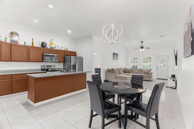 dining area with ceiling fan with notable chandelier, sink, and light tile patterned floors