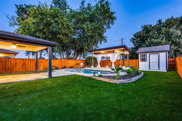 view of yard featuring ceiling fan, a shed, and a fenced in pool