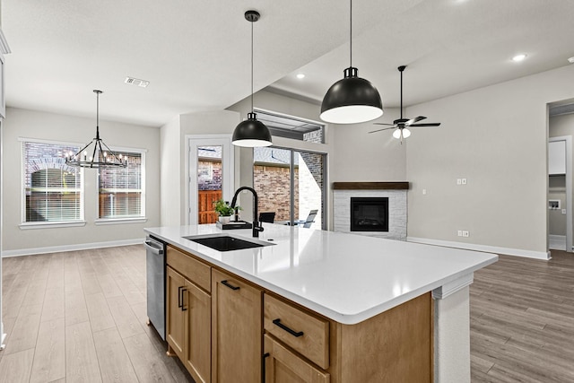 kitchen with hanging light fixtures, an island with sink, dishwasher, and sink