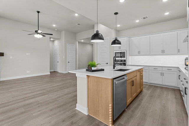 kitchen featuring sink, a kitchen island with sink, white cabinets, built in microwave, and stainless steel dishwasher