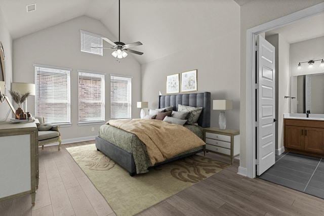 bedroom with ceiling fan, ensuite bathroom, vaulted ceiling, and light hardwood / wood-style flooring