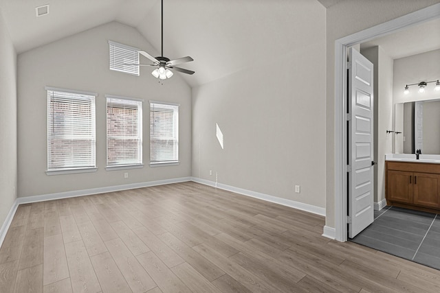 unfurnished living room featuring vaulted ceiling, sink, ceiling fan, and light hardwood / wood-style flooring