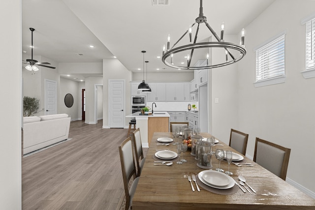 dining room featuring sink, ceiling fan with notable chandelier, and light hardwood / wood-style floors