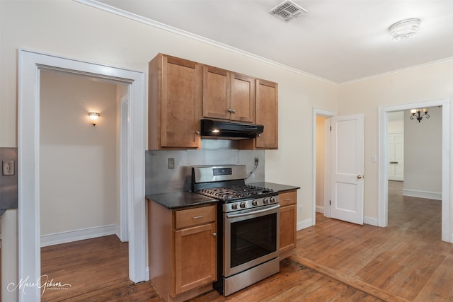 kitchen with light hardwood / wood-style floors, stainless steel gas range, exhaust hood, a chandelier, and ornamental molding