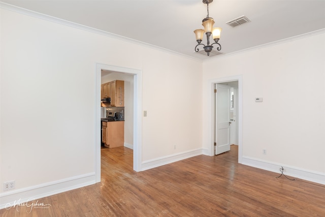 unfurnished room with an inviting chandelier, ornamental molding, and hardwood / wood-style floors