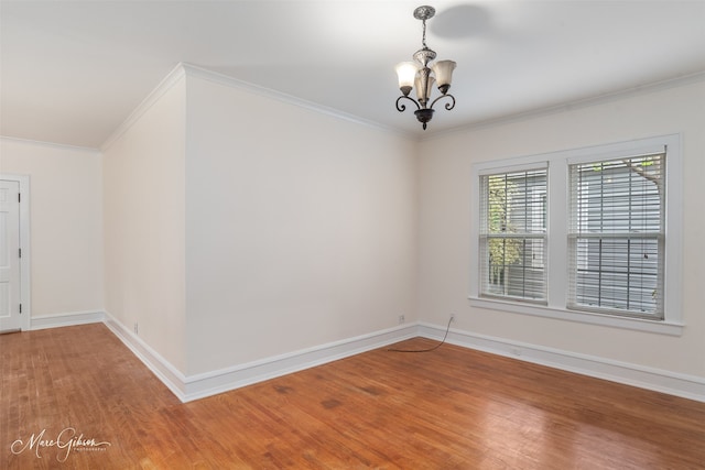 spare room with a notable chandelier, hardwood / wood-style floors, and ornamental molding