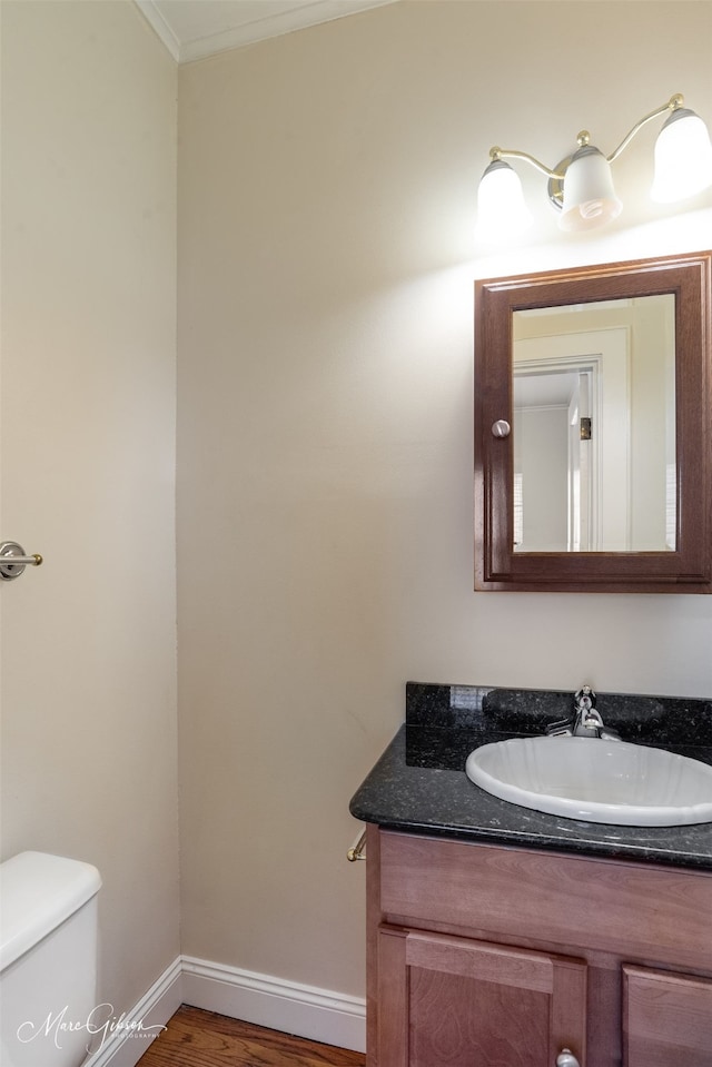 bathroom featuring hardwood / wood-style floors, crown molding, toilet, and vanity