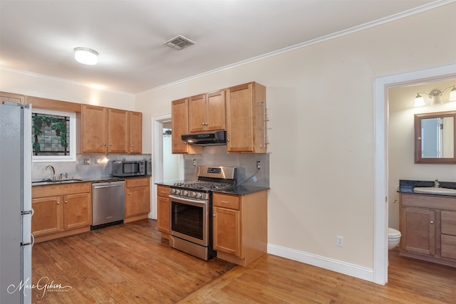 kitchen featuring extractor fan, stainless steel appliances, sink, backsplash, and light hardwood / wood-style floors