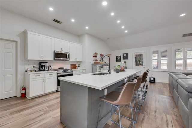 2908 Torreya Dr, Mckinney, TX 75071 - kitchen featuring stainless steel appliances, a sink, vaulted ceiling, light wood-style flooring, and tasteful backsplash