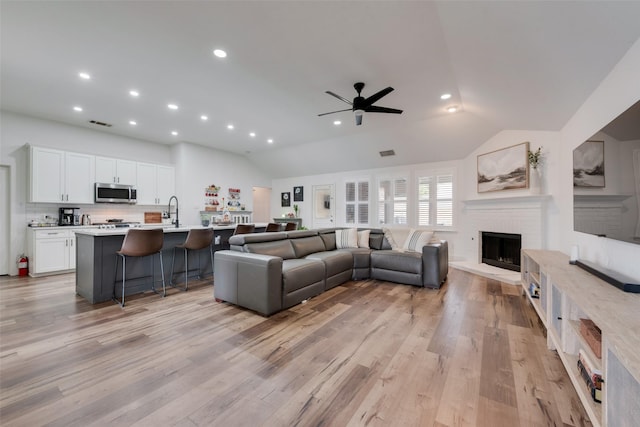 2908 Torreya Dr, Mckinney, TX 75071 - living room featuring vaulted ceiling, a ceiling fan, a brick fireplace, recessed lighting, and light wood-type flooring
