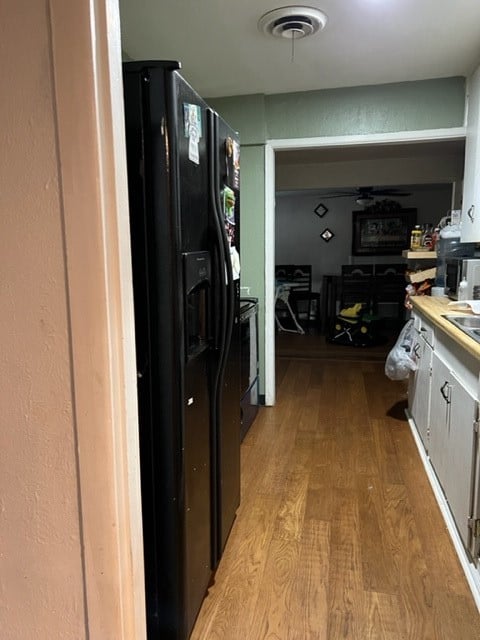 kitchen featuring light wood-type flooring and black fridge with ice dispenser