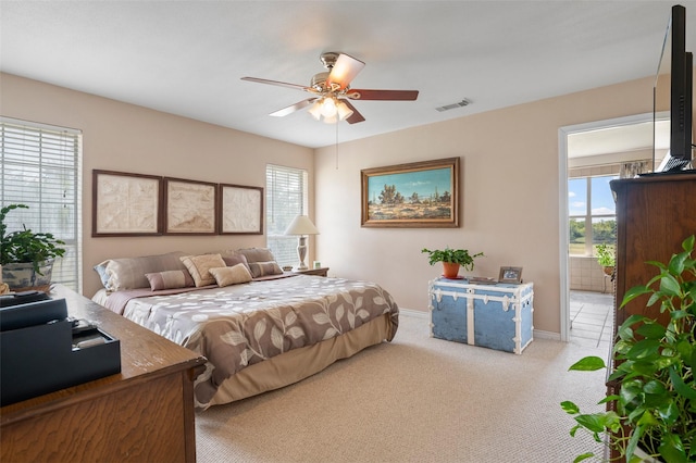 carpeted bedroom with multiple windows, ensuite bathroom, and ceiling fan
